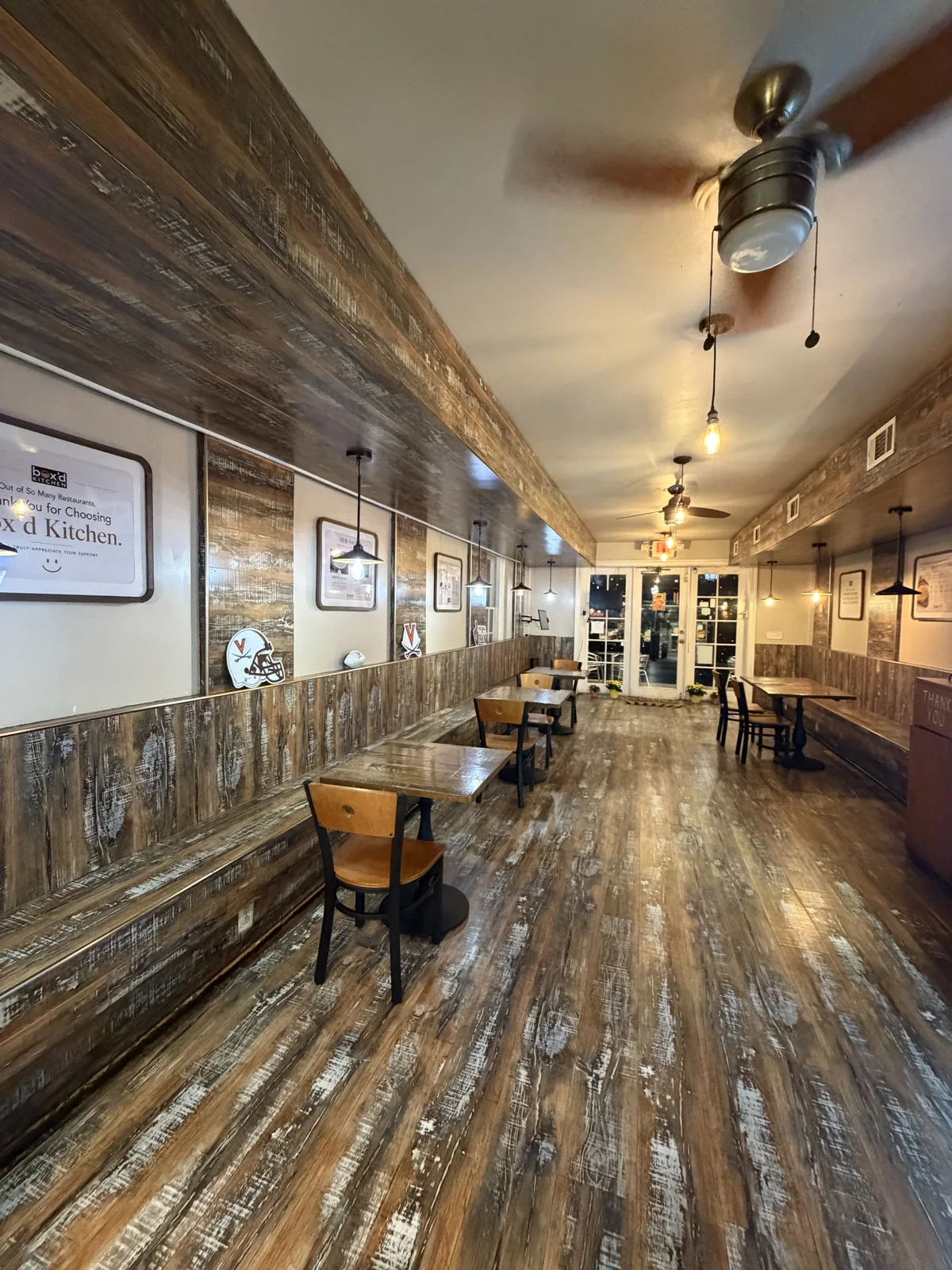Wooden benches, tables and warm pendant lights inside Box’d Kitchen on West Main Street