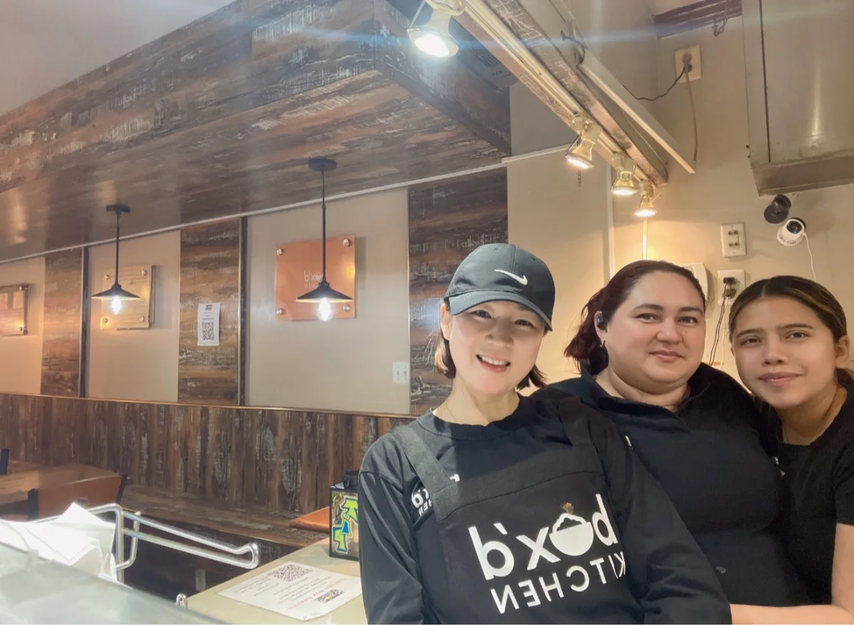 Nayoung Yum smiling with two members of the Box’d Kitchen team