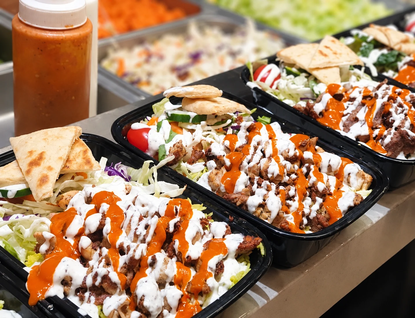 Individually prepared rice boxes with protein, salad, housemade sauces and pita at the Box’d Kitchen counter